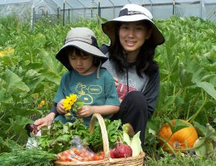 Mother and son sitting in pumkin patch with harvest basket